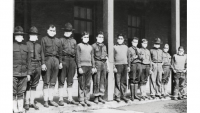 Black and white image of young men lined up wearing masks