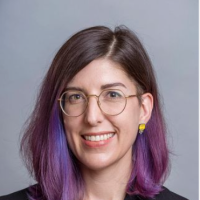 Woman smiling in black jacket and eyeglasses, dark long straight hair has purple ends