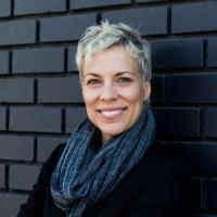 Headshot of Jae Sevelius against a black brick wall