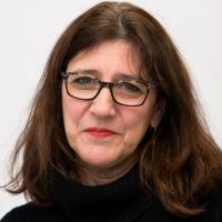 Maura Spiegel looks at the camera, she has long brown hair and eyeglasses.